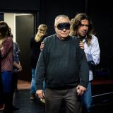 Osoby z czarnymi opaskami na oczach, prowadzone przez pracowników instytucji kultury podczas szkolenia.