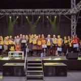 Liczna grupa osób pozuje na scenie ze świadectwami dostępności.